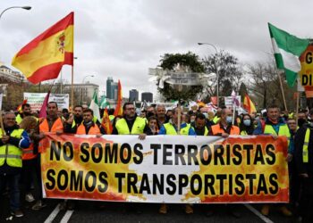 Demonstrators hold a banner reading “we are not terrorists, we are truckers”, during a protest called by striking hauliers against soaring fuel prices in Madrid, on March 25, 2022. – The Spanish government on March 25, 2022 offered a rebate and a onetime cash payment to end a truckers’ strike over soaring fuel prices that has led to food shortages in supermarkets across the country. Drivers and truck owners belonging to the group called Platform for the Defence of Transport have since March 14 been blocking roads and ports to draw attention to the rise in fuel prices, which have been exacerbated by Russia’s invasion of Ukraine. (Photo by Pierre-Philippe MARCOU / AFP)