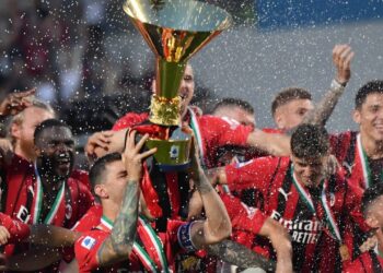 AC Milan’s Italian defender Alessio Romagnoli (C-L), AC Milan’s French forward Olivier Giroud (Bottom R) and AC Milan’s players celebrate with the winner’s trophy after AC Milan won the Italian Serie A football match between Sassuolo and AC Milan, securing the “Scudetto” championship on May 22, 2022 at the Mapei – Citta del Tricolore stadium in Sassuolo. (Photo by Tiziana FABI / AFP)