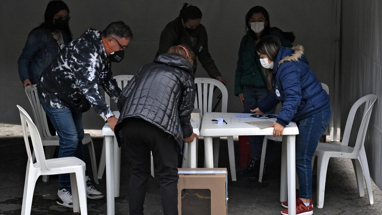 People in charge of the polling station where Colombian left-wing presidential candidate Gustavo Petro is expected to vote, accomodate their post during the presidential runoff election in Bogota, on June 19, 2022. – Colombians vote for a new president in an election filled with uncertainty, as former guerrilla Gustavo Petro and millionaire businessman Rodolfo Hernandez vie for power in a country saddled with widespread poverty, violence and other woes. (Photo by Juan BARRETO / AFP)