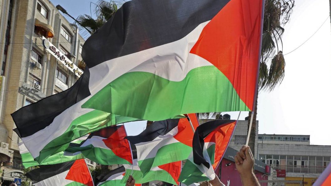 Palestinians wave their country’s national flag as they march during a rally in Ramallahduring a rally in Ramallah in the occupied West Bank, on August 7, 2022. – Islamic Jihad militants in Gaza said today they had agreed to a Cairo-brokered ceasefire to end three days of intense conflict with Israel that has left at least 41 Palestinians dead (Photo by ABBAS MOMANI / AFP)