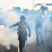 A police officer throws smoke while people protest against the government of Peruvian President Dina Boluarte in Lima on January 17, 2023. – Peruvian President Dina Boluarte asked this Tuesday to the hundreds of protesters from various regions of the country who are heading to Lima to protest against their government to do so in “peace and calm.” (Photo by ERNESTO BENAVIDES / AFP)