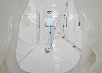 This photo taken on March 17, 2022, shows a staff member, wearing personal protective equipment (PPE), walking at the Fire Eye laboratory, a temporary Covid-19 coronavirus testing facility, before it opens in Yantai in China’s eastern Shandong province. (Photo by AFP) / China OUT