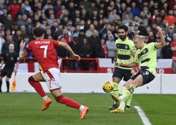 Manchester City’s Norwegian striker Erling Haaland (R) takes a shot during the English Premier League football match between Nottingham Forest and Manchester City at The City Ground in Nottingham, central England, on February 18, 2023. (Photo by JUSTIN TALLIS / AFP)