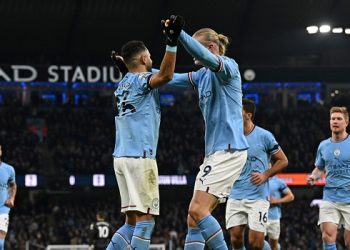 Manchester City’s Algerian midfielder Riyad Mahrez (centre left) celebrates with Manchester City’s Norwegian striker Erling Haaland (centre right) after scoring their third goal from the penalty spot during the English Premier League football match between Manchester City and Aston Villa at the Etihad Stadium in Manchester, north west England, on February 12, 2023. (Photo by Paul ELLIS / AFP).