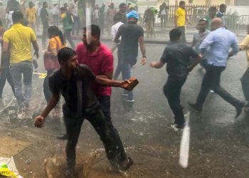 An activist of Sri Lanka’s main opposition and Samagi Jana Balawegaya party throws back stones towards police during a protest held to urge the government to hold local council election as scheduled in Colombo on February 20, 2023. (Photo by ISHARA S. KODIKARA / AFP)