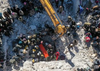 An aerial picture shows rescuers searching the rubble of buildings for casualties and survivors in the village of Salqin in Syria’s rebel-held northwestern Idlib province at the border with Turkey following an earthquake, on February 7, 2023. (Photo by Omar HAJ KADOUR / AFP)