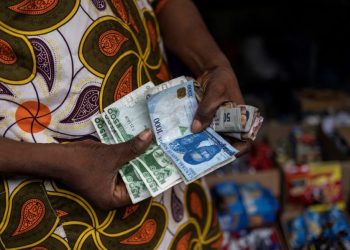 A vendor shows old and newly introduced Nigerian Naira banknotes in a market in Lagos on February 16, 2023. – Nigeria has been struggling with a shortage in physical cash since the Central Bank of Nigeria (CBN) began to swap old bills of the local naira currency for new, re-designed ones, leading to a shortfall in banknotes. (Photo by Michele Spatari / AFP)