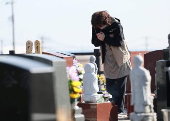 People visit a cemetery at Namie town of Fukushima Prefecture on March 11, 2023, on the 12th anniversary of the 9.0 magnitude earthquake which triggered a tsunami and nuclear disaster. (Photo by STR / JIJI PRESS / AFP) / Japan OUT / JAPAN OUT