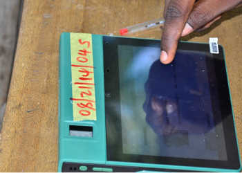 In this file photo, an Independent National Electoral Commission (INEC) official uses a Bimodal Voter Accreditation System (BVAS) to check the details of a voter at a polling station in Maiduguri on February 25, 2023, during Nigeria’s presidential and general election. (Photo by Audu MARTE / AFP)