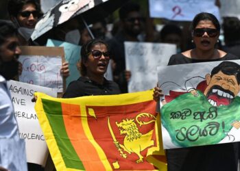 Protestors hold banners and placards during a demonstration against the surge in prices and shortage of fuel and other essential commodities in Colombo on April 4, 2022 – Sri Lanka’s president offered to share power with the opposition on April 4, as protests escalated across the country demanding his resignation over worsening shortages of food, fuel and medicines. (Photo by Ishara S. KODIKARA / AFP)