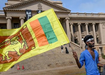 A man wears a headband with a slogan against interim Sri Lankan President Ranil Wickremesinghe as he waves the Sri Lankan national flag near the Presidential secretariat in Colombo on 17 July 2022. (Photo by Arun SANKAR / AFP)