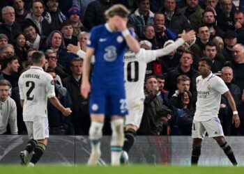 Real Madrid's Brazilian striker Rodrygo Goes (R) celebrates scoring the opening goal during the Champions League quarter-final second-leg football match between Chelsea and Real Madrid at Stamford Bridge in London on April 18, 2023. (Photo by Glyn KIRK / AFP)