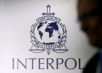 FILE PHOTO: A man passes an Interpol logo during the handing over ceremony of the new premises for Interpol’s Global Complex for Innovation, a research and development facility, in Singapore September 30, 2014. REUTERS/Edgar Su/File Photo