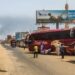 People wait next to passenger buses as smoke billows in an area in Khartoum where fighting continues between Sudan’s army and the paramilitary forces on April 28, 2023. – Fighting raged in Sudan on April 28, despite rival forces agreeing to extend a truce aimed to stem nearly two weeks of warfare that has killed hundreds and caused widespread destruction. (Photo by – / AFP)