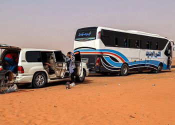 Passengers take out luggage as they disembark off a vehicle at a rest-point by a desert road at al-Gabolab in Sudan’s Northern State, about 100 kilometres northwest of the capital, on April 25, 2023. (Photo by AFP)