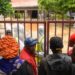 Friends and relatives of victims stand outside the gates as they await the start of postmortem analysis on victims of the Shakahola massacre at the Malindi district funeral home, in Malindi on May 1, 2023. – A high-profile Kenyan pastor appeared in court on May 28, suspected of links to the murder of dozens of people found in mass graves that has been dubbed the “Shakahola forest massacre”. Ezekiel Odero, the flamboyant head of the New Life Prayer Centre and Church, was arrested on Thursday in the coastal town of Malindi and is accused of the “mass killing” of his followers. (Photo by SIMON MAINA / AFP)