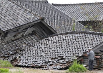 A man looks at a house which collapsed after a 6.5 magnitude earthquake hit the area the day before, in the city of Suzu, Ishikawa prefecture on May 6, 2023. – Aftershocks shook Japan a day after the powerful quake left at least one person dead, with officials assessing damage on May 6 from the jolt that destroyed several buildings. (Photo by STR / JIJI Press / AFP) / Japan OUT / JAPAN OUT