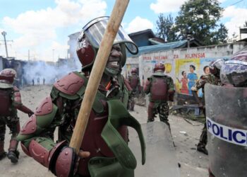 Anti-riot police officers react to the effects of tear gas after one of their canisters fired at protesters was lobbed back at them during confrontations at a mass rally called by the opposition leader Raila Odinga who claims the last Kenyan presidential election was stolen from him and blames the government for the hike of living costs in the country, in Mathare, Nairobi, on March 27, 2023. – Police fired tear gas to disperse anti-government protests on March 27, 2023 over the high cost of living, after the opposition vowed demonstrations would go ahead despite a police ban. (Photo by Tony KARUMBA / AFP)