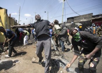 Protesters throw rocks in the direction of police on the third day of confrontations between authorities and supporters of the Kenyan opposition during anti-government protests in Kibera, Nairobi, on July 21, 2023. (Photo by Tony KARUMBA / AFP)