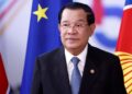 (FILES) Cambodia’s Prime Minister and Association of Southeast Asian Nations (ASEAN) president Hun Sen gestures as he arrives to attend the EU-ASEAN summit at the European Council headquarters in Brussels on December 14, 2022, with EU and ASEAN flags in the background. – Cambodian Prime Minister Hun Sen, one of the world’s longest-serving leaders, said on July 26, 2023 he will resign and hand power to his son, after almost four decades of hardline rule. (Photo by Kenzo TRIBOUILLARD / AFP)