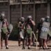 Kenyan Police officers watch protesters as they block the street during a mass rally called by the opposition leader Raila Odinga who claims the last Kenyan presidential election was stolen from him and blames the government for the hike of living costs in Kibera, Nairobi on March 27, 2023. – Police fired tear gas to disperse anti-government protests on March 27, 2023 over the high cost of living, after the opposition vowed demonstrations would go ahead despite a police ban. (Photo by YASUYOSHI CHIBA / AFP)