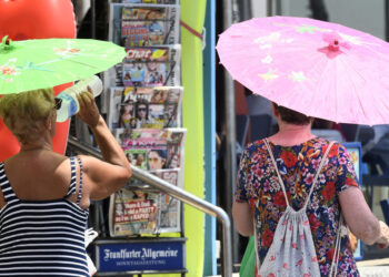 Two women use umbrellas to protect themselves from the sun / AFP PHOTO / JOSE JORDAN