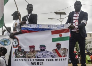 Protesters hold a Russian flag and a banner with images of (from L to R): General Abdourahamane Tiani, Nigers new strongman, Burkina Faso’s junta leader Captain Ibrahim Traore, leader of Mali’s junta, Assimi Goita, and Guinea’s junta leader, Colonel Mamady Doumbouya, during a demonstration on independence day in Niamey on August 3, 2023. – Security concerns built on August 3, 2023 ahead of planned protests in coup-hit Niger, with France demanding safety guarantees for foreign embassies as some Western nations reduced their diplomatic presence. (Photo by – / AFP)