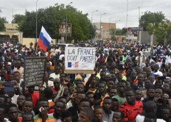 Protesters hold an anti-France placard during a demonstration (Photo by – / AFP)