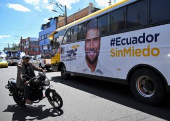 A man rides a motorcycle next to a bus with an image of Ecuador’s presidential candidate, Jan Topic, during a campaign rally in Quito on August 4, 2023. – Ecuador’s President Guillermo Lasso called for snap elections for August 20 after he dissolved Congress in May to avoid an impeachment trial for allegedly allowing corruption in state-owned companies. (Photo by Rodrigo BUENDIA / AFP)