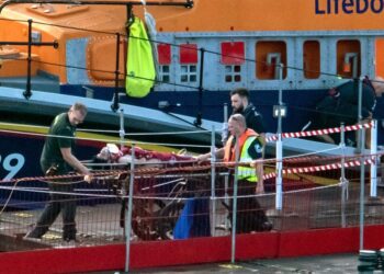 Paramedics assist a migrant picked up at sea while attempting to cross the English Channel, after they were picked up by a UK Royal National Lifeboat Institution (RNLI) lifeboat and brought to the Marina in Dover, southeast England, on August 12, 2023. – Six Afghan males died when a migrant boat heading to Britain sank in the Channel early Saturday, French officials said, as a search continued to find those still missing. (Photo by Stuart Brock / AFP)