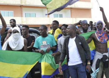 Residents holding Gabon national flags celebrate in Libreville on August 30, 2023 after a group of Gabonese military officers appeared on television announcing they were “putting an end to the current regime” and scrapping official election results that had handed another term to veteran President Ali Bongo Ondimba. –  (Photo by – / AFP)