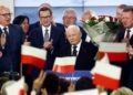 Polish Deputy Prime Minister and leader of the Law and Justice party (PiS) party, Jaroslaw Kaczynski (C) and Polish Prime Minister Mateusz Morawiecki (3L) of the Law and Justice party react with supporters at the party’s headquarters in Warsaw, Poland on October 15, 2023, after the presentation of the first exit poll results of the country’s parliamentary elections. (Photo by Wojtek Radwanski / AFP)