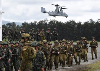 Philippine and Australian soldiers march in formation while a US marines V-22 Osprey hovers above during military exercise Alon (wave), a joint amphibious landing drill held at a naval base in San Antonio town in Zambales province, north of Manila on August 25, 2023. (Photo by TED ALJIBE / AFP)