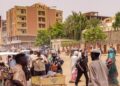 Pedestrians and vehicles move along a road outside a branch of the Central Bank of Sudan in the country’s eastern city of Gedaref on July 9, 2023. – Many civil servants in Sudan have been going on without a salary since the Sudanese army and the paramilitary Rapid Support Forces took up arms against each other. When the first blasts shook Khartoum on April 15, banks there shuttered their doors, and branches nationwide have since struggled to provide services because they are cut off from headquarters in the capital. Since then, the only government salaries that have been paid are the army’s. (Photo by – / AFP)