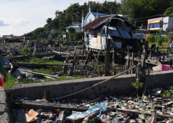 This photo taken on October 13, 2023, shows a person walking past debris on waterfront plots where houses once stood before Super Typhoon Haiyan struck in 2013, in Tacloban city, Leyte province. – The Philippines, which endures more than 20 major storms a year, has plenty of experience dealing with disasters. But that did not prepare them for one of the strongest typhoons on record. Haiyan unleashed winds of up to 315 kilometres (195 miles) an hour that flattened towns and cities across a 600-kilometre stretch of central islands. (Photo by Ted ALJIBE / AFP) /