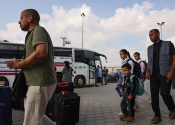 People prepare to board a bus as dual national Palestinians and foreigners get ready to cross the Rafah border point with Egypt, in the southern Gaza Strip. Egypt will help evacuate “about 7,000” foreigners and dual nationals from the war-ravaged Gaza Strip, the foreign ministry said, with officials saying some 400 people were expected to cross on November 2. (Photo by Mohammed ABED / AFP)