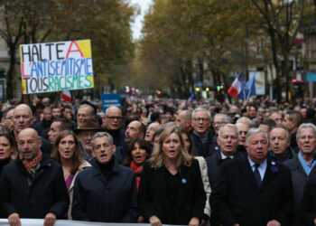 French Senate President Gerard Larcher (5thL), President of the French National Assembly Yael Braun-Pivet (4thL), surrounded by French Prime Minister Elisabeth Borne (2ndR), France’s former President Nicolas Sarkozy (3rdL) and France’s former President Francois Hollande (R) sing the French national anthem as they stand behind a banner which reads as “For The Republic, Against anti-Semistism” during a march against anti-semitism in Paris, on November 12, 2023. (Photo by Thomas SAMSON / AFP)