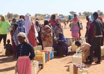 Refugees fleeing the conflict in Sudan queue with their jerrycans to queue to collect drinking water from the Doctors Without Borders (MSF) distribution point at the Ourang refugee camp in Adre on December 7, 2023. – The conflict raging in Sudan has thrown hundreds of thousands of people into exile, to flee the violence in Darfur, where the international community is worried about ethnic cleansing, many finding refuge in camps of eastern Chad. (Photo by Denis Sassou Gueipeur / AFP)