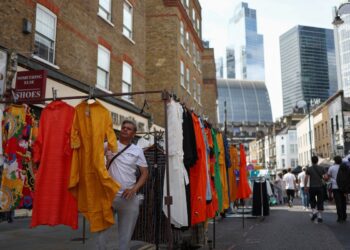 (FILES) Shoppers browse stalls in Petticoat Lane Market, against the backdrop of The City of London financial district in London on August 11, 2023. - Britain's economy unexpectedly shrank in the third quarter, official data showed Friday December 22, raising fears of a potential recession before an election due next year. (Photo by HENRY NICHOLLS / AFP)