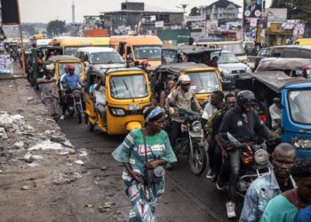 A woman walks through traffic in the popular Ndjili neighborhood in Kinshasa on December 15, 2023. (Photo by JOHN WESSELS / AFP)