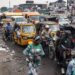 A woman walks through traffic in the popular Ndjili neighborhood in Kinshasa on December 15, 2023. (Photo by JOHN WESSELS / AFP)