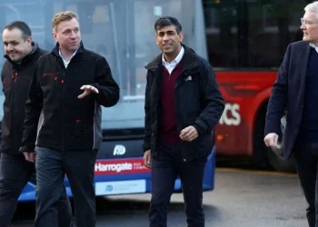 Britain’s Prime Minister Rishi Sunak (2R) reacts during a visit to a bus depot in Harrogate, northern England on February 12, 2024. (Photo by CARL RECINE / POOL / AFP)