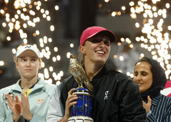 Iga Swiatek of Poland lifts the trophy after winning against Elena Rybakina of Kazakhstan (L) during their women’s singles final match at the Qatar Open tennis tournament in Doha, during a podium ceremony attended by Sheikha Al-Mayassa bint Hamad bin Khalifa Al Thani (R), sister of Qatar’s ruling Emir on February 17, 2024. (Photo by KARIM JAAFAR / AFP)