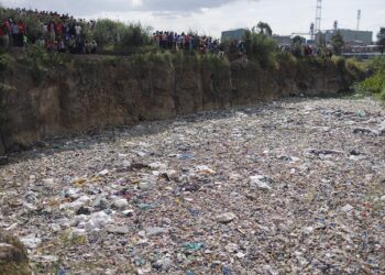 People stand on the edge of a dumpsite where six bodies were found at the landfill in Mukuru slum, Nairobi, on July 12, 2024.  (Photo by SIMON MAINA / AFP)