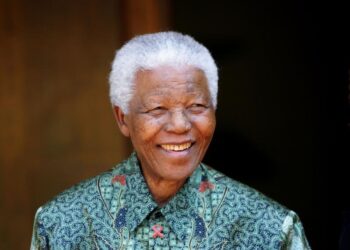 Former South African President Nelson Mandela smiles for photographers after a meeting with actor Tim Robbins at Mandela's home in Johannesburg September 22, 2005. REUTERS/Mike Hutchings