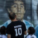 Walter Rotundo (C) poses for a photo with his twins daughters Mara (L) and Dona, named in honour of the football star Diego Maradona, in front of murals painted outside of Diego Maradona stadium in Buenos Aires, on November 16, 2021. A 39-year-old Argentinian, a Diego Maradona fanatic like millions of his compatriots, became the proud father of a little “Diego” on the anniversary of the idol’s death. In a few days, he will join his two 10-year-old sisters, named Mara, and Dona. TOMAS CUESTA / AFP